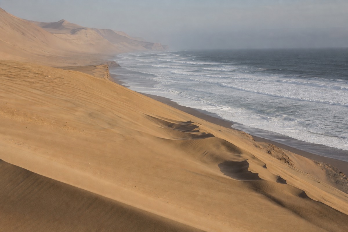 Sandboarding in Huacachina on the slopes of a coastal desert dune